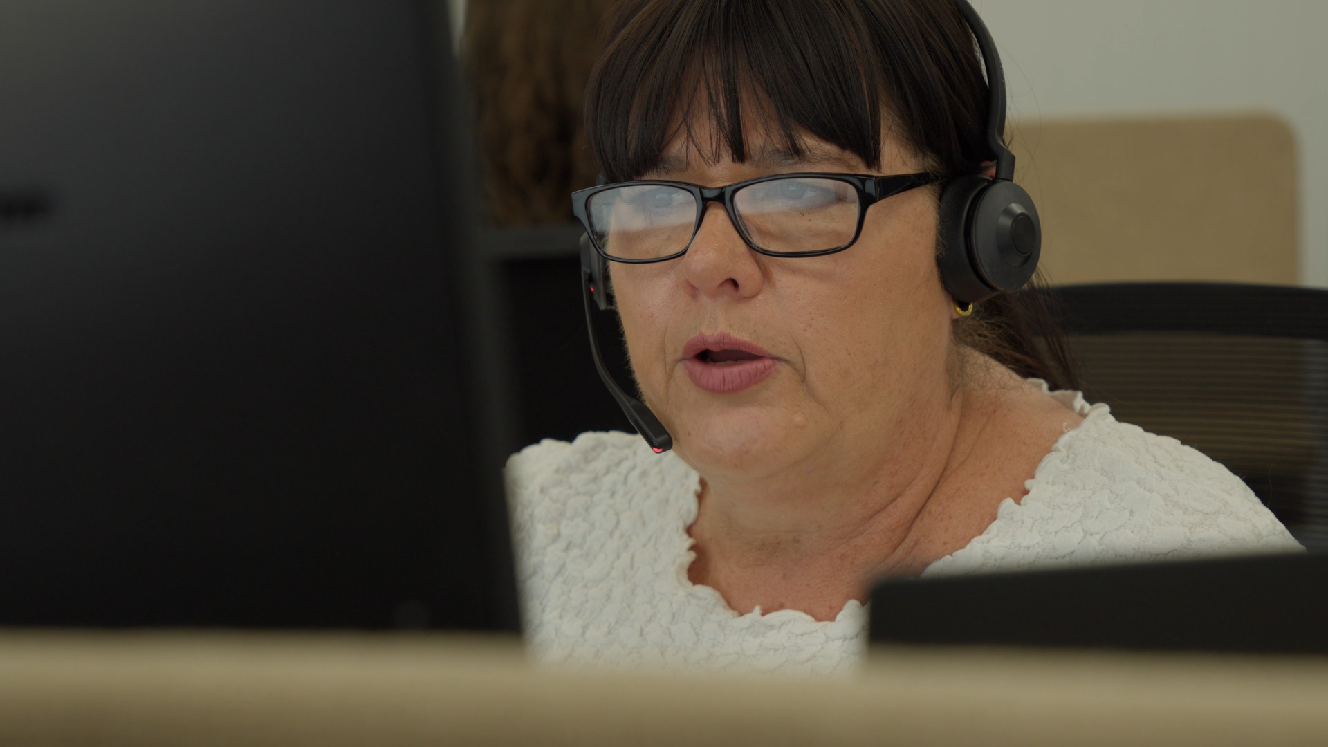 Woman with glasses and headset on talking to a computer taking a customer call